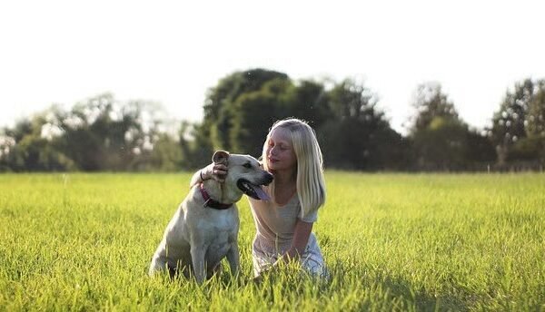 a woman sitting in a field with a dog