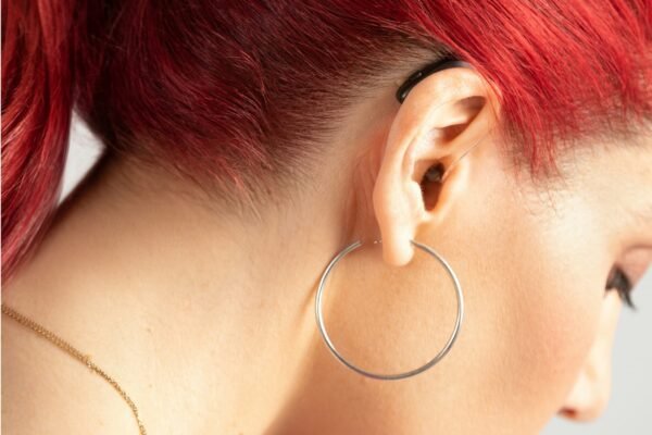 a woman with red hair and hoop earrings with a hearing aid